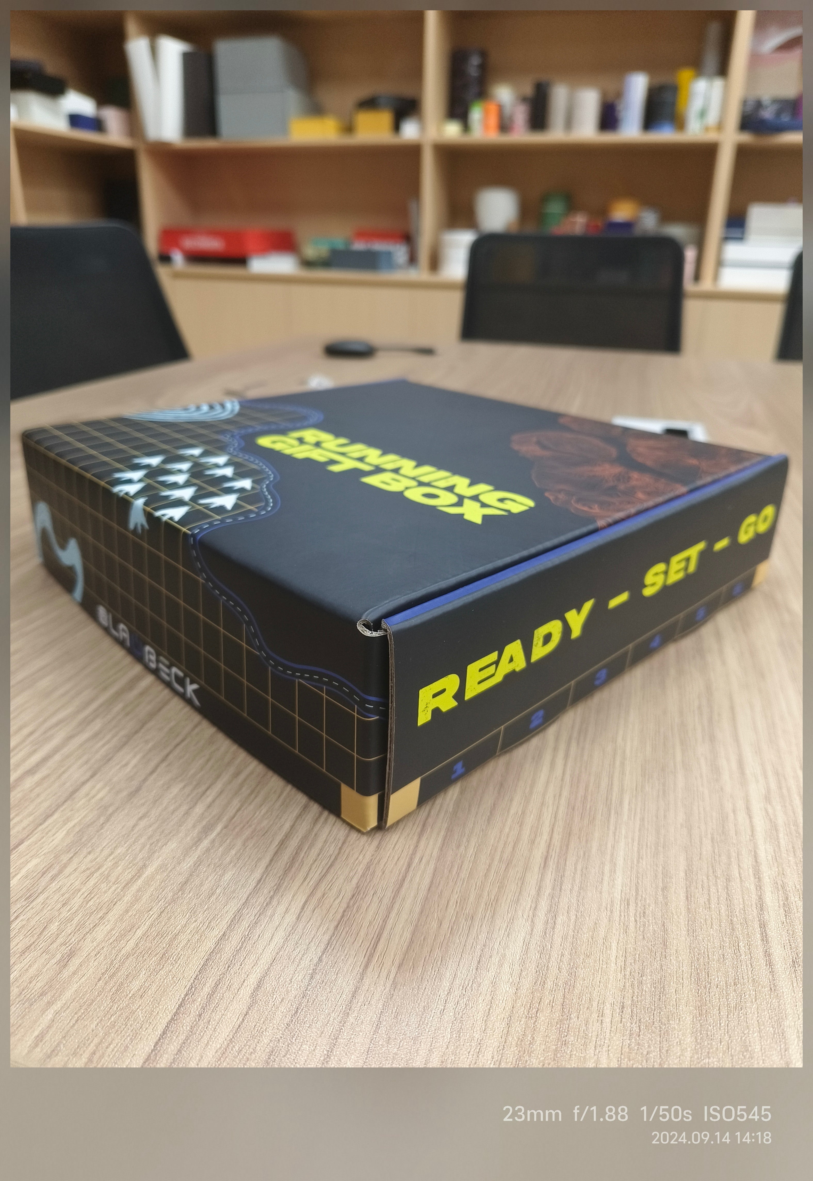 Black and blue box labeled 'READY-SET-GO' on a desk with a blurred office background